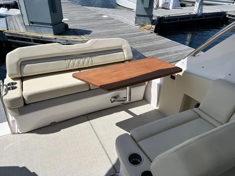 Slide: The Image of 2021 Regal 33 Express boat interior with beige seating and wooden table at dock. - 6