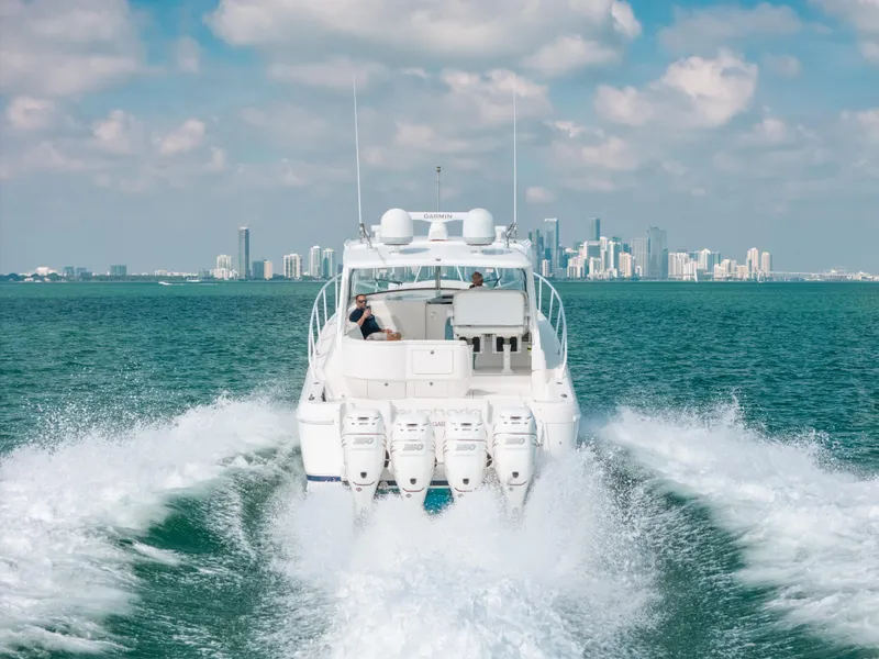 Slide: The Image of 2009 Intrepid 475 Sport Yacht cruising on open water with city skyline in background. - 12