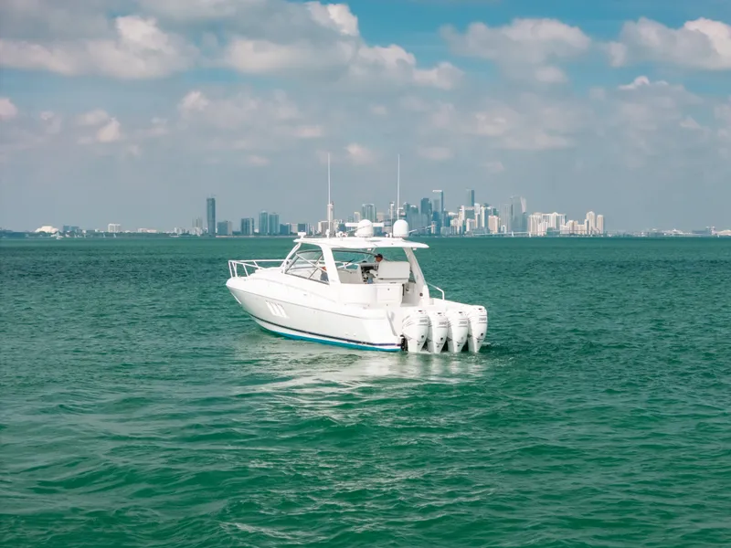 Slide: The Image of 2009 Intrepid 475 Sport Yacht cruising on open water with city skyline backdrop. - 24