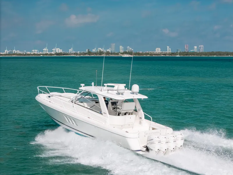 Slide: The Image of 2009 Intrepid 475 Sport Yacht cruising on turquoise waters, city skyline in background. - 6
