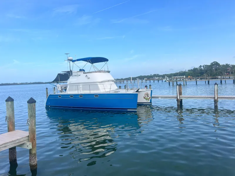 The Image of 2006 PDQ MV34 boat docked on calm water under clear blue sky. - 0