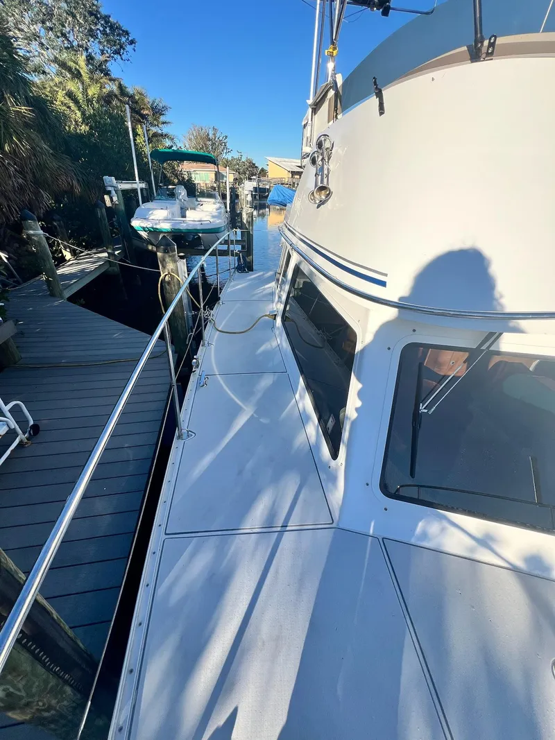 Slide: The Image of 2006 PDQ MV34 boat docked near a wooden pier on a sunny day. - 10