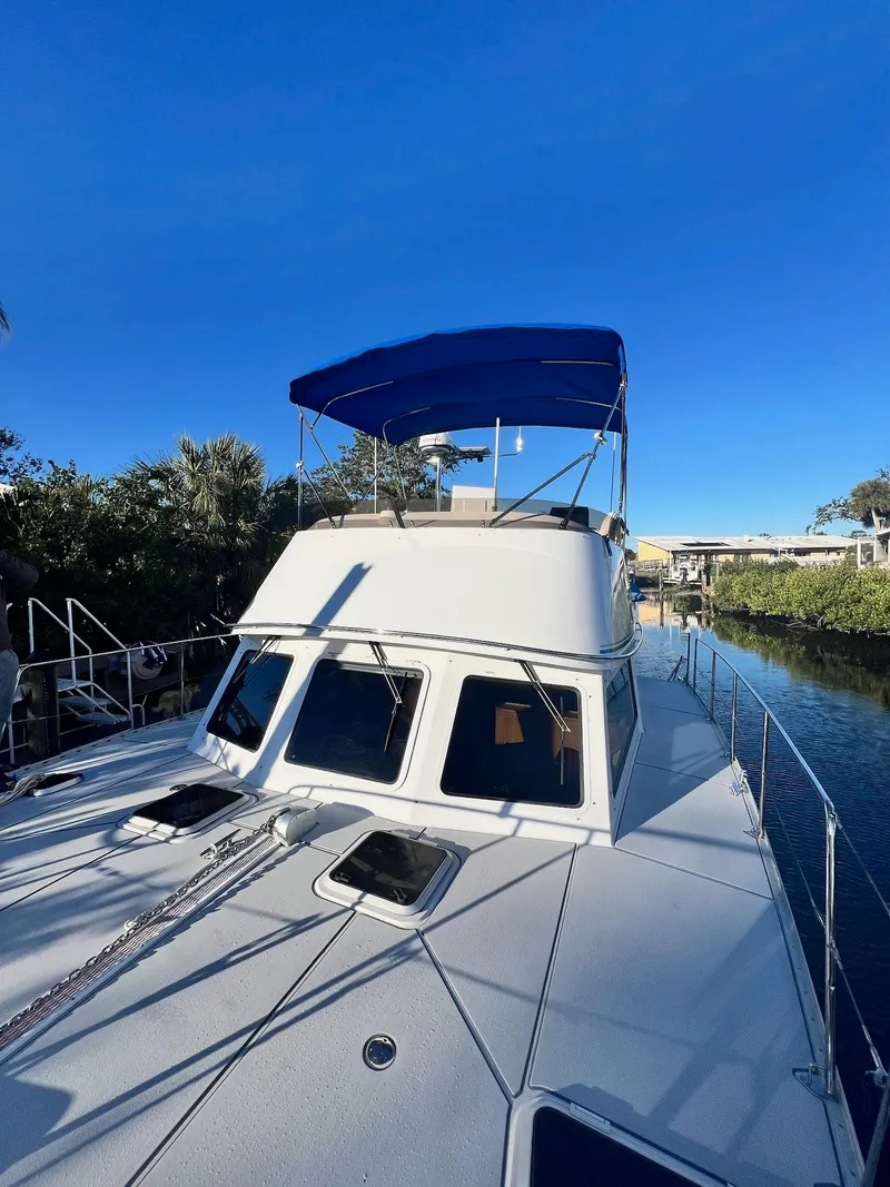 Slide: The Image of 2006 PDQ MV34 boat with blue canopy on a sunny day by the water. - 12