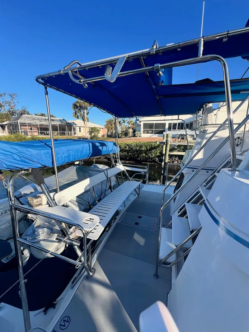 Slide: The Image of 2006 PDQ MV34 boat deck with blue canopy and seating, docked near waterfront homes. - 14