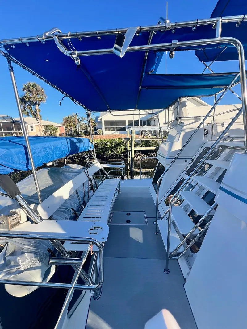 Slide: The Image of 2006 PDQ MV34 boat deck with blue canopy and seating area, docked at marina. - 15