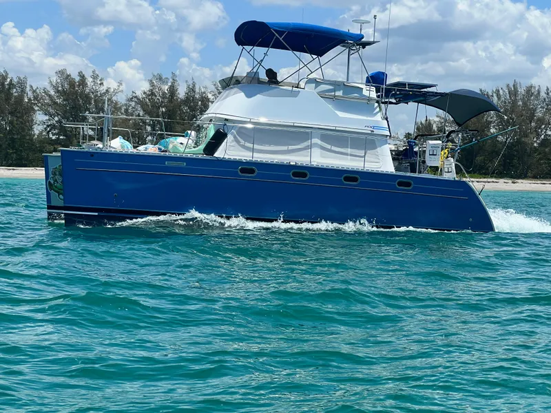 Slide: The Image of Blue PDQ MV34 boat cruising on clear water, 2006 model, with a canopy and scenic background. - 2