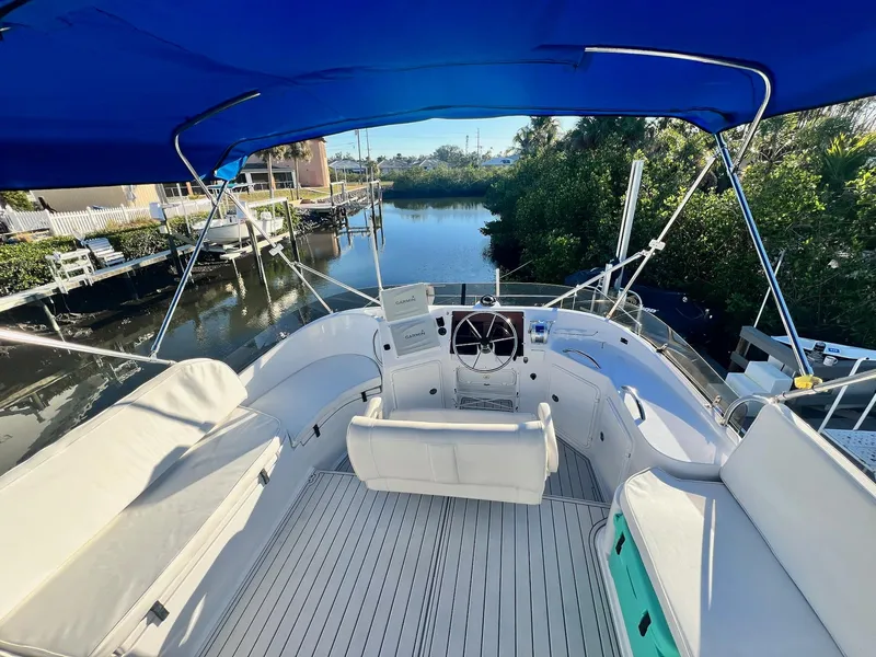 Slide: The Image of 2006 PDQ MV34 boat interior with blue canopy, docked by a serene waterway. - 23