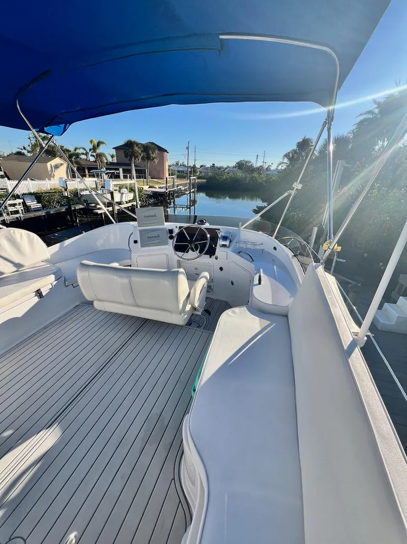 Slide: The Image of 2006 PDQ MV34 boat with blue canopy, docked in a serene waterfront setting. - 25