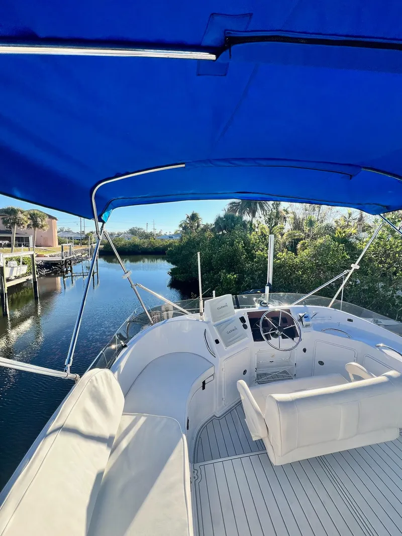 Slide: The Image of 2006 PDQ MV34 boat with blue canopy, docked near lush greenery and calm water. - 26