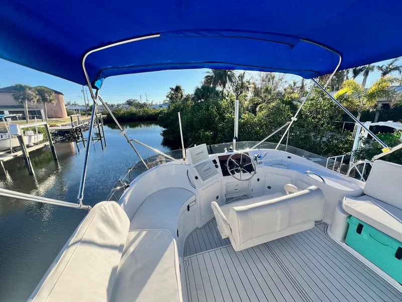 Slide: The Image of 2006 PDQ MV34 boat with blue canopy, docked near lush greenery. - 27