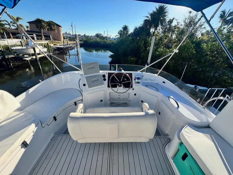 Slide: The Image of 2006 PDQ MV34 boat cockpit with white seating, steering wheel, and lush waterfront view. - 30
