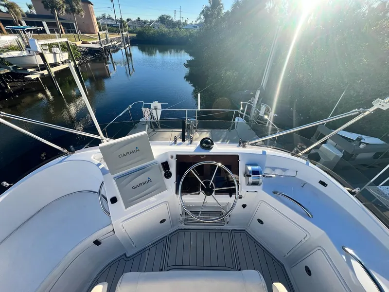 Slide: The Image of 2006 PDQ MV34 boat helm with steering wheel, Garmin equipment, and scenic waterway view. - 31