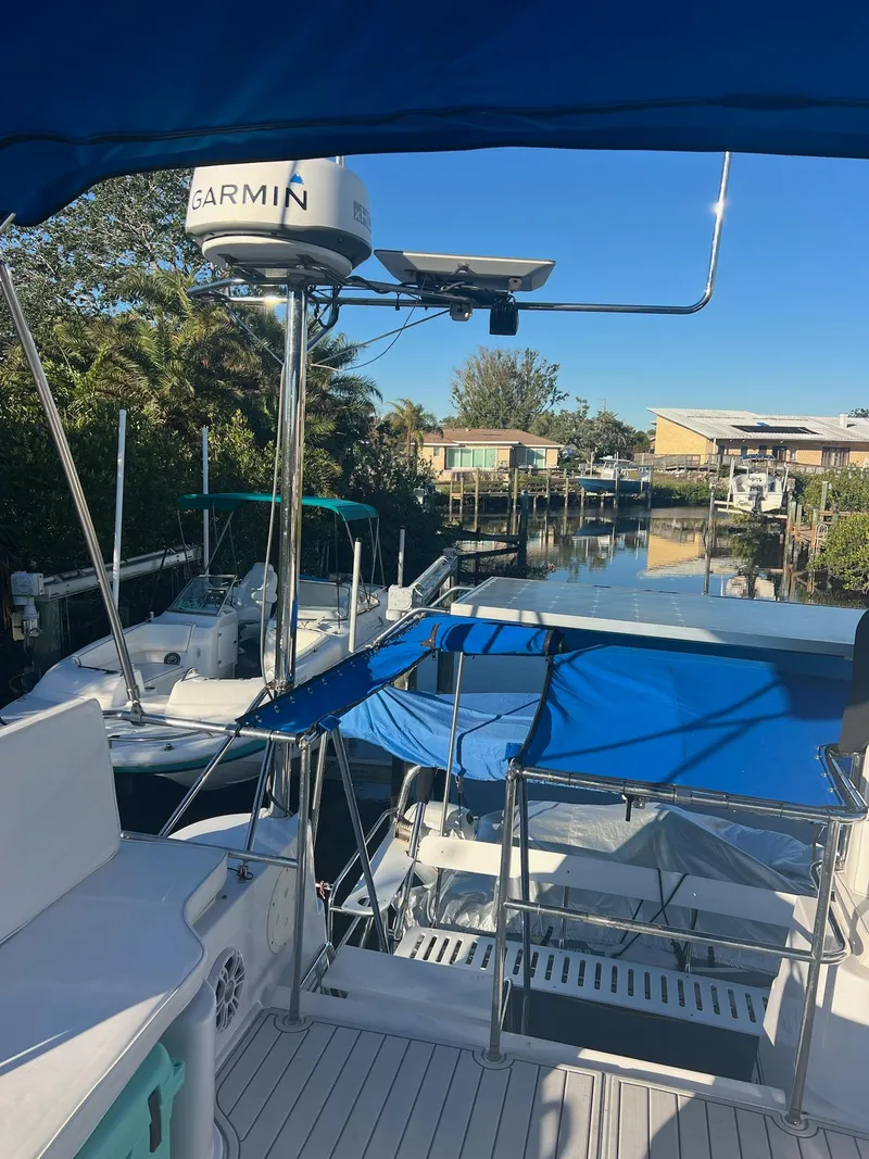 Slide: The Image of 2006 PDQ MV34 boat docked in a serene canal setting with blue canopy. - 36