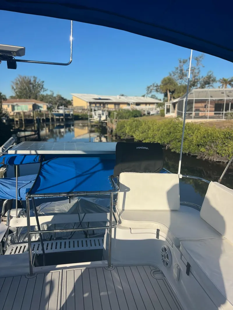 Slide: The Image of 2006 PDQ MV34 boat docked, featuring spacious deck and blue canopy, with waterfront view. - 39