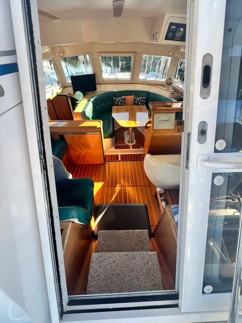 Slide: The Image of Interior view of 2006 PDQ MV34 boat, featuring a cozy seating area and wooden flooring. - 42