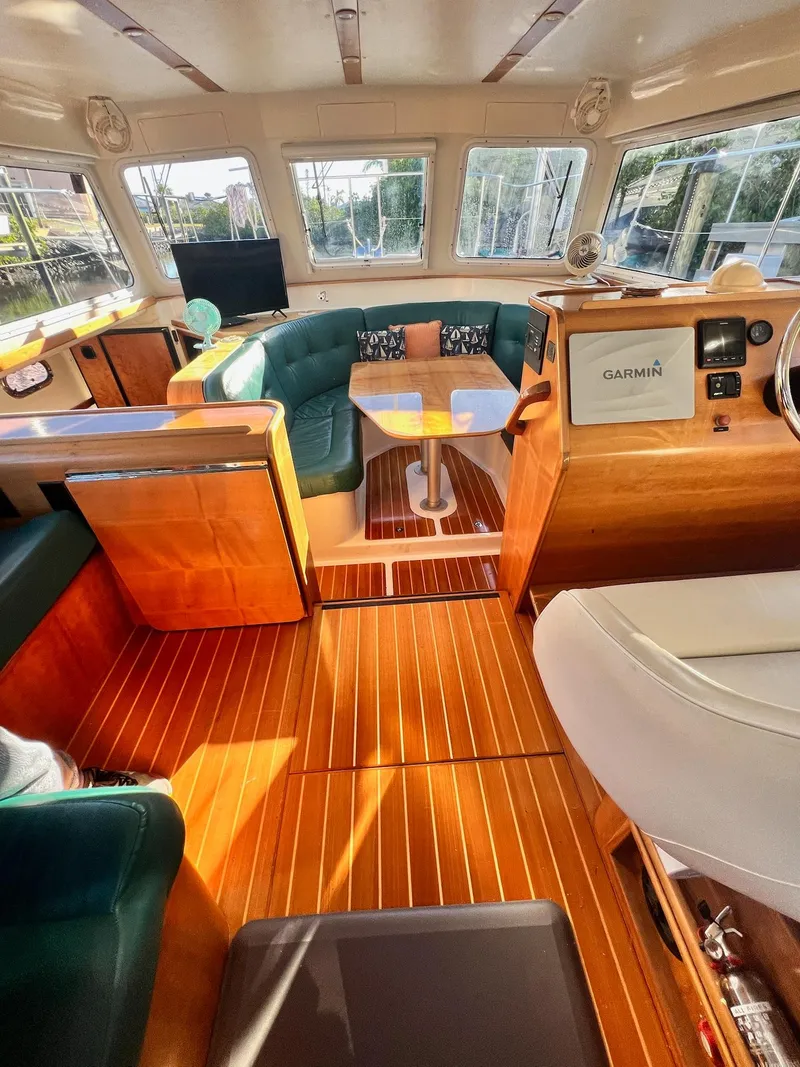 Slide: The Image of Interior of a 2006 PDQ MV34 boat with wooden flooring and green seating. - 47
