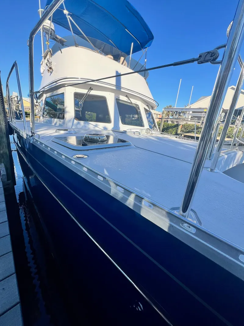 Slide: The Image of 2006 PDQ MV34 boat docked, featuring blue hull and white deck under clear sky. - 7