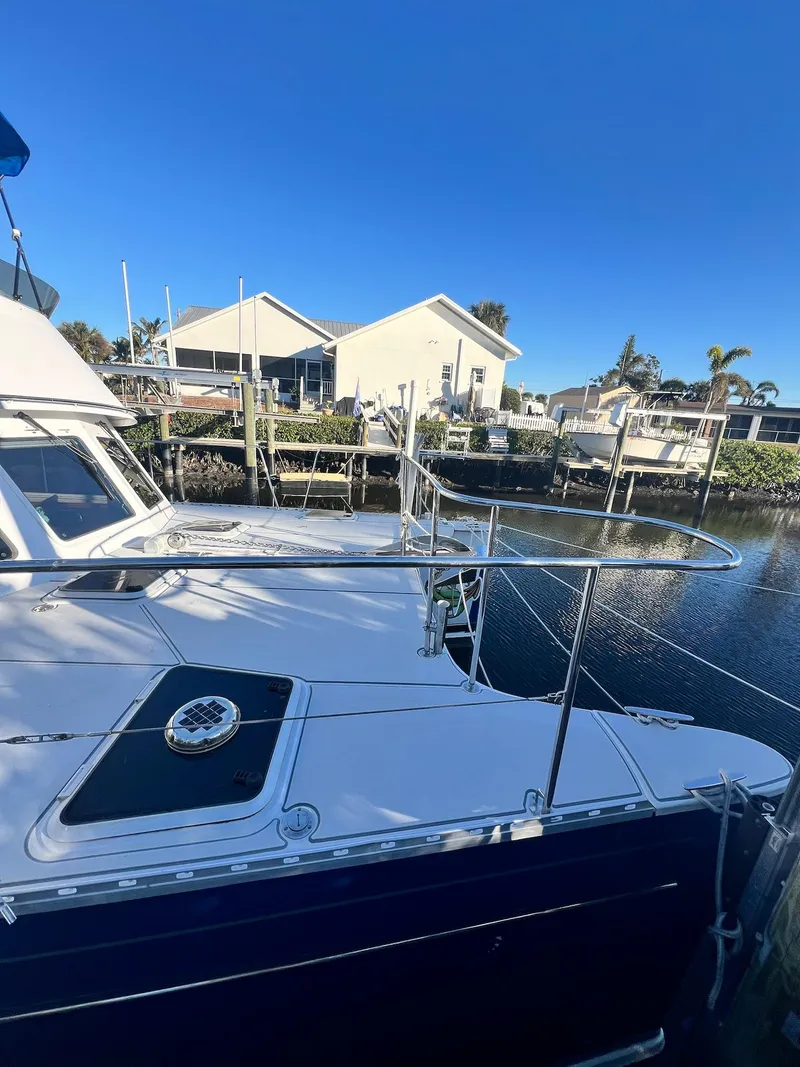 Slide: The Image of 2006 PDQ MV34 boat docked near waterfront homes under clear blue sky. - 8