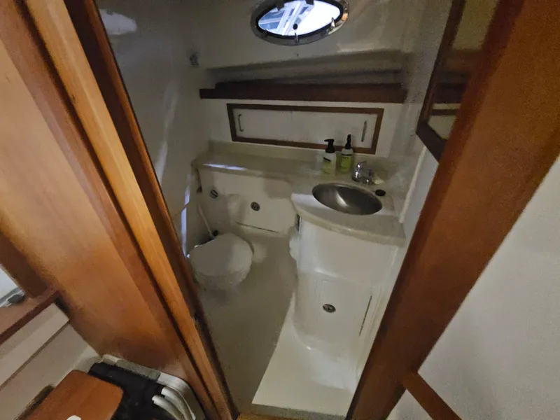 Slide: The Image of 2012 Back Cove 30 boat bathroom with sink, toilet, and porthole window. - 18