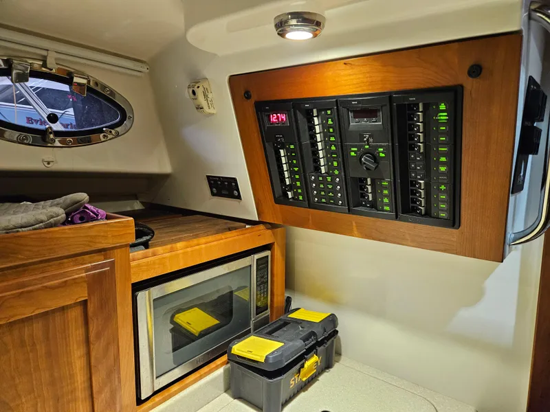 Slide: The Image of 2012 Back Cove 30 yacht interior with control panel, microwave, and storage area. - 19