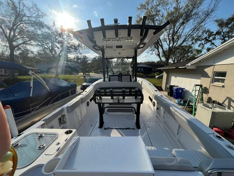 Slide: The Image of 2023 Sea Fox 268 Commander boat interior with seating and console, under sunny sky. - 18