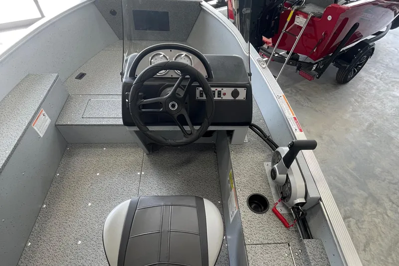 Slide: The Image of 2025 Lund 1400 Fury SS boat interior with steering wheel and controls. - 2