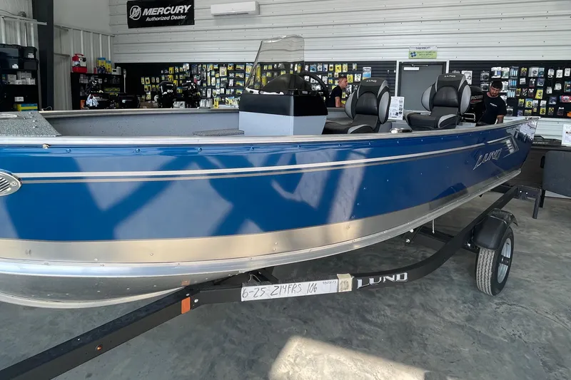 Slide: The Image of 2025 Lund 1400 Fury SS boat in showroom, blue exterior, on trailer. - 8