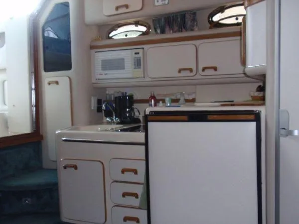 Slide: The Image of 1994 Sea Ray 330 Sundancer interior kitchen with microwave, sink, and refrigerator. - 10