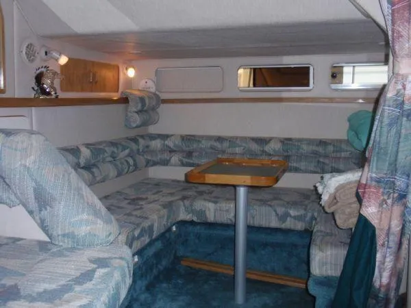 Slide: The Image of 1994 Sea Ray 330 Sundancer cabin with cushioned seating and table, featuring cozy interior design. - 11