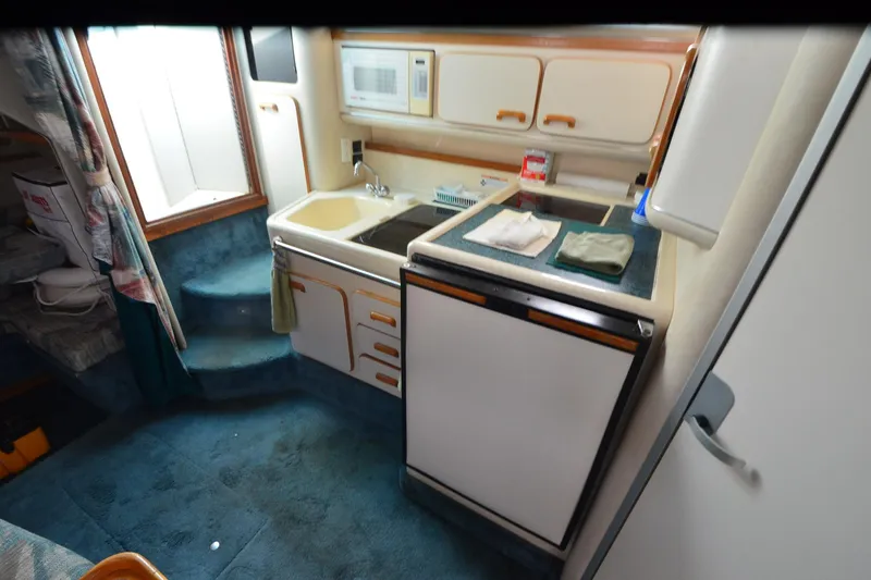 Slide: The Image of 1994 Sea Ray 330 Sundancer interior kitchen with sink, microwave, and storage cabinets. - 22
