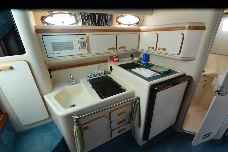 Slide: The Image of 1994 Sea Ray 330 Sundancer kitchen with sink, microwave, and storage cabinets. - 26