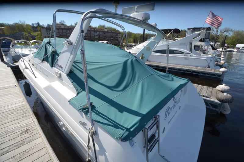 Slide: The Image of 1994 Sea Ray 330 Sundancer docked with green cover, American flag in background. - 4