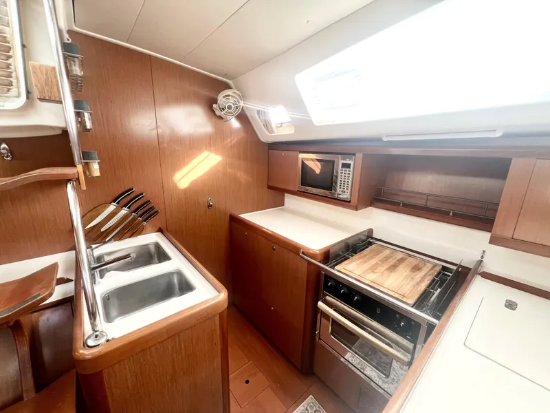 Slide: The Image of 2008 Beneteau 46 yacht kitchen with wooden cabinetry, sink, stove, and microwave. - 10