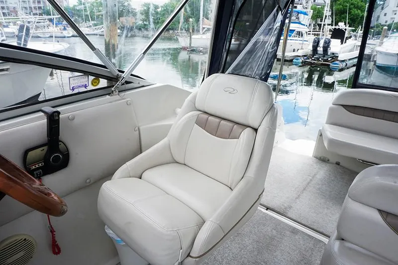 Slide: The Image of Interior of a 2000 Regal Commodore 2660 boat with white seating and marina view. - 14