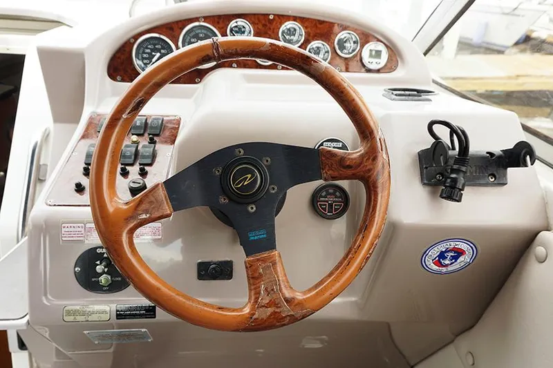 Slide: The Image of Steering wheel and dashboard of 2000 Regal Commodore 2660 boat, featuring wood accents and controls. - 21