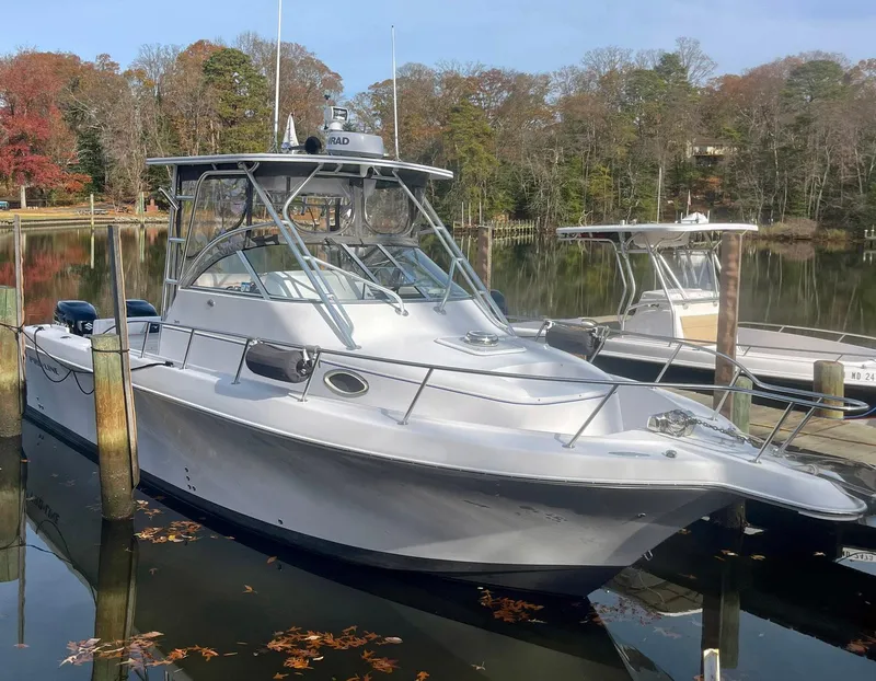Slide: The Image of 2003 Pro-Line 30 WALKAROUND boat docked in a serene marina setting. - 2