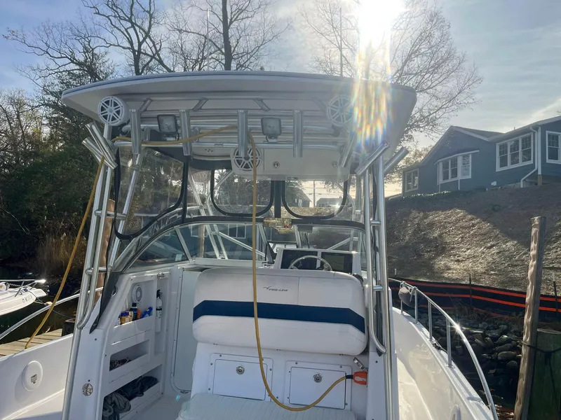 Slide: The Image of 2003 Pro-Line 30 Walkaround boat with seating and storage, docked near waterfront homes. - 9