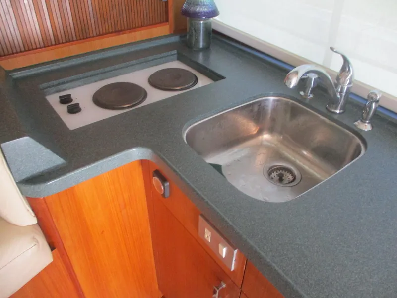 Slide: The Image of 1997 Ocean Yachts 40 Super Sport kitchen with sink and stovetop, featuring wood cabinetry. - 30