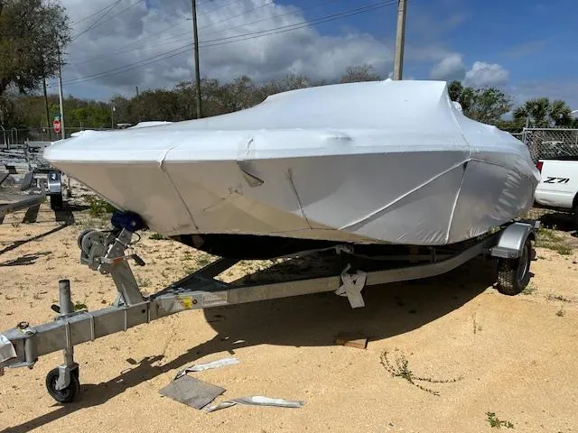 The Image of 2025 Bayliner Element M17 boat covered on a trailer, parked on sandy ground. - 0
