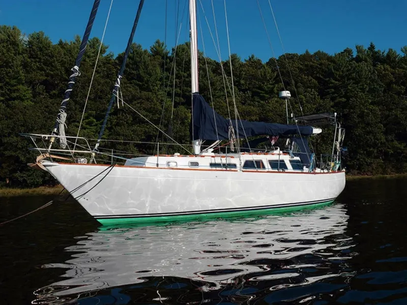 Slide: The Image of 1973 Challenger 40 sailboat on calm water, surrounded by lush green trees. - 1