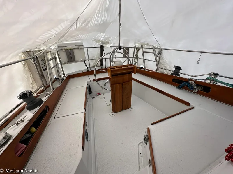 Slide: The Image of 1973 Challenger 40 sailboat cockpit with wooden helm and white interior under cover. - 15