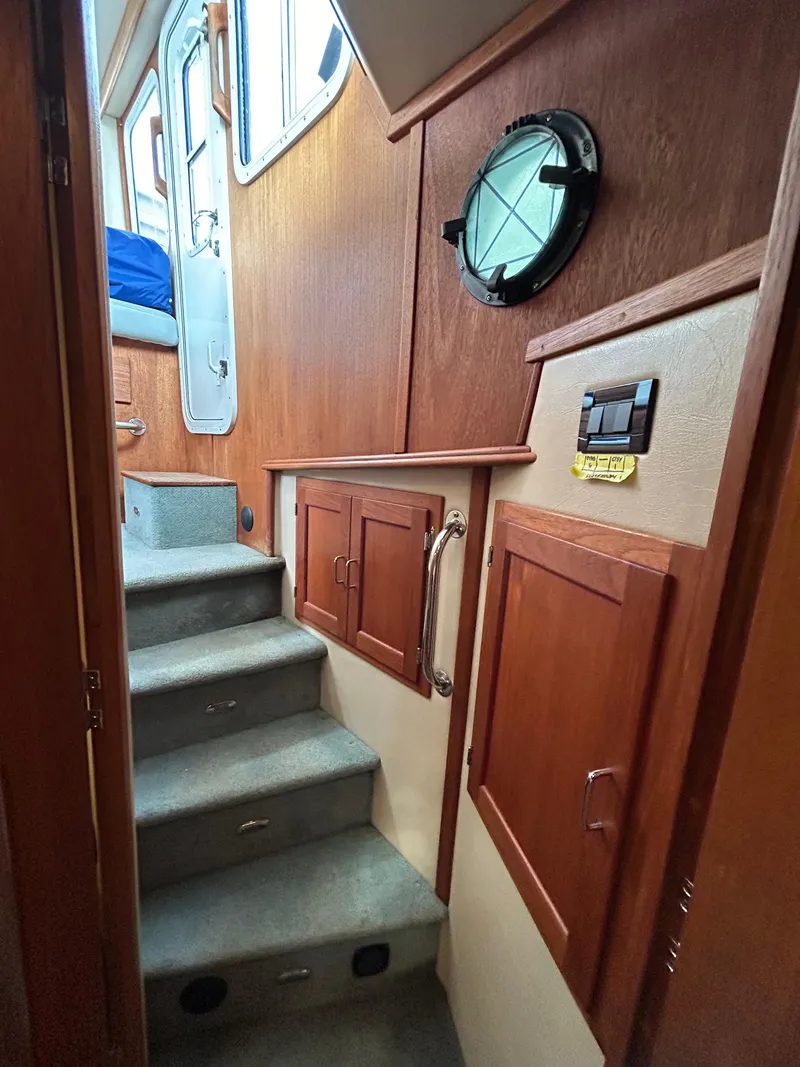 Slide: The Image of Stairway inside 2003 American Tug 34, featuring wooden cabinets and a porthole window. - 10