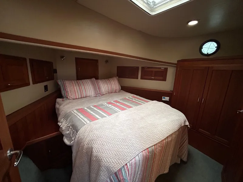 Slide: The Image of Cozy bedroom in 2003 American Tug 34 with striped bedding and wooden cabinetry. - 12