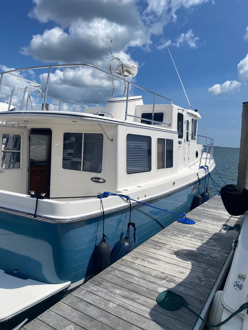 Slide: The Image of 2003 American Tug 34 docked, featuring a white and blue exterior under a partly cloudy sky. - 3