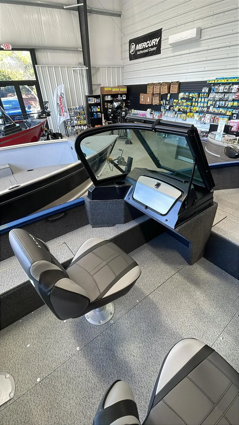 Slide: The Image of 2025 Lund 1650 Rebel XL Sport boat interior with seating and dashboard in showroom. - 10