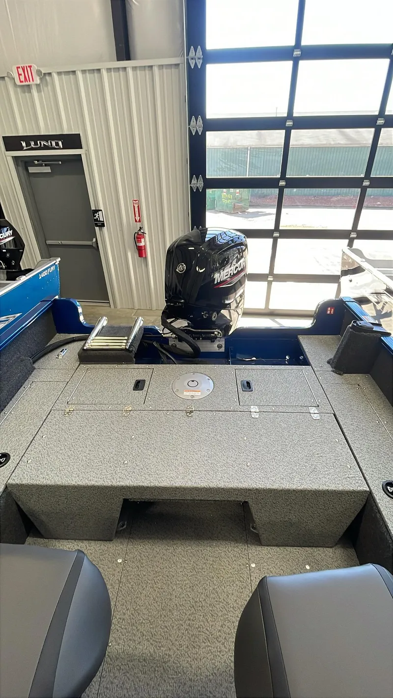 Slide: The Image of 2025 Lund 1650 Rebel XL Sport boat interior with motor, in a showroom setting. - 6