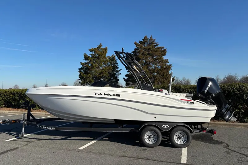 Slide: The Image of 2024 Tahoe T21 boat on trailer in parking lot, clear sky background. - 8