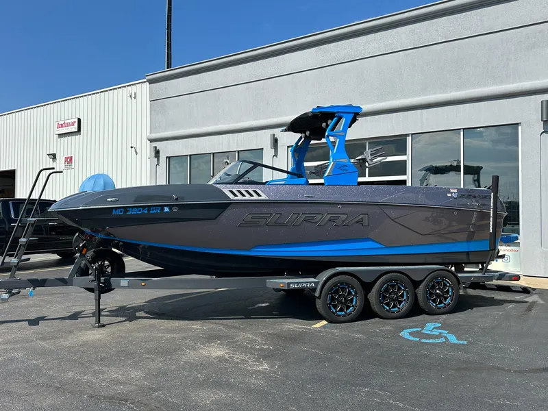 Slide: The Image of 2022 Supra SE boat on trailer outside dealership, featuring sleek design and modern features. - 1