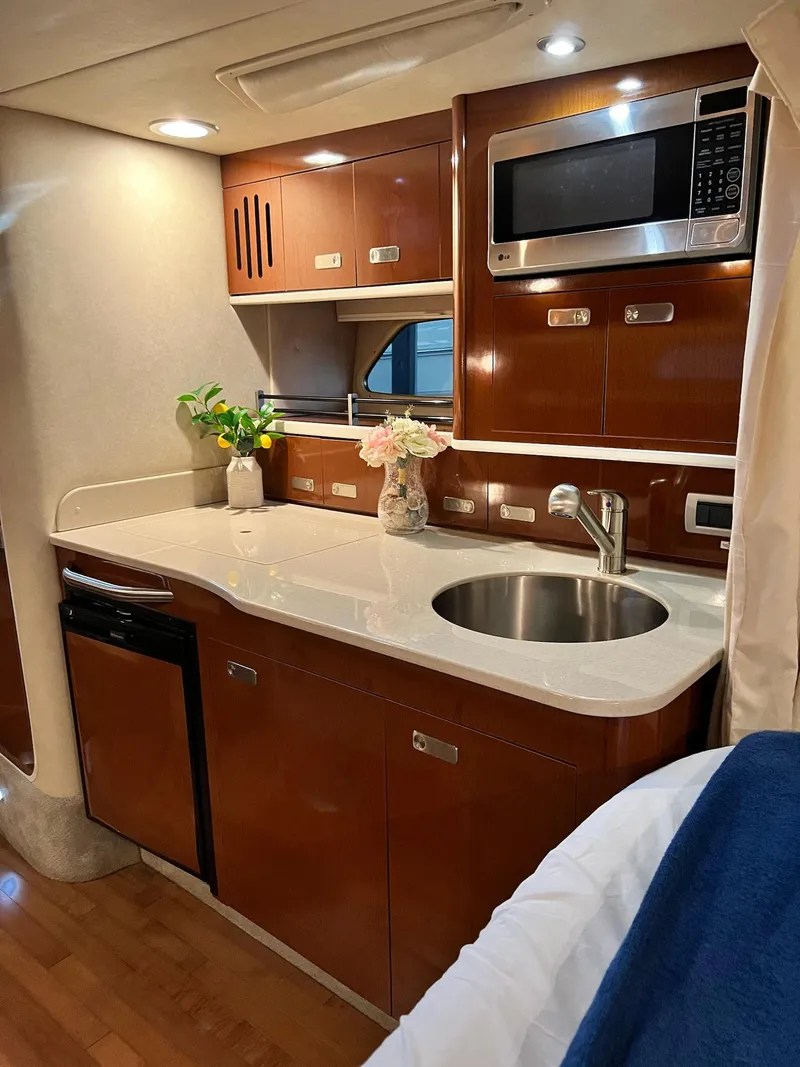 Slide: The Image of 2011 Sea Ray 350 Sundancer interior kitchen with sink, microwave, and wooden cabinetry. - 28