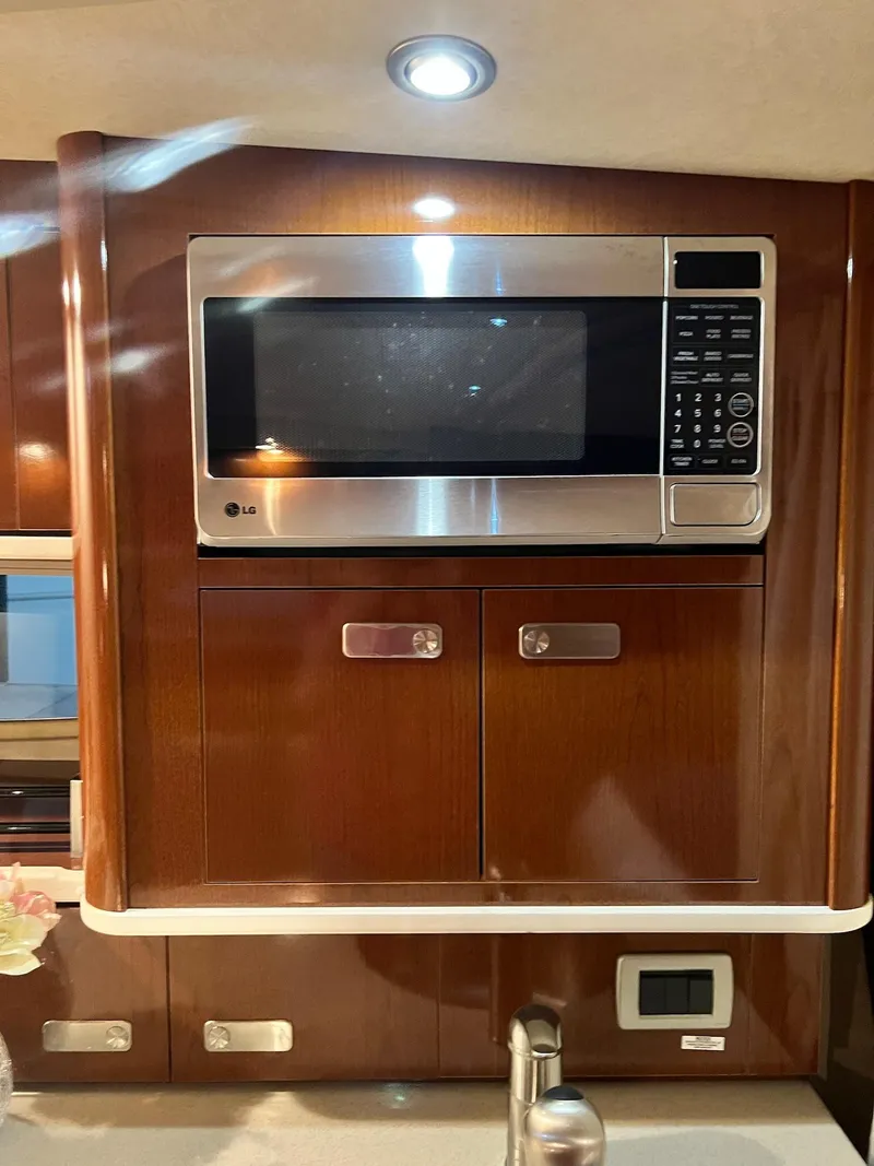 Slide: The Image of 2011 Sea Ray 350 Sundancer interior with microwave and wooden cabinetry. - 29